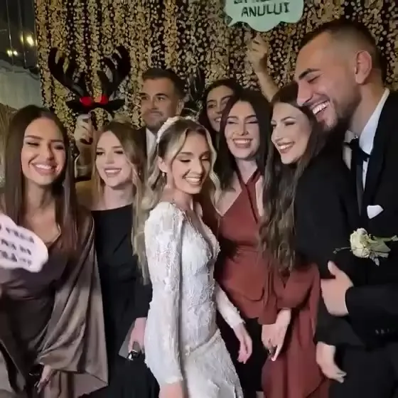 Mireasa și invitații râzând cu accesorii, la cabina foto